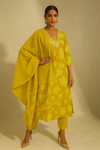 Woman wearing a yellow traditional outfit with a beige background