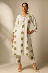 Woman wearing a white kurta with green polka dots on a beige background