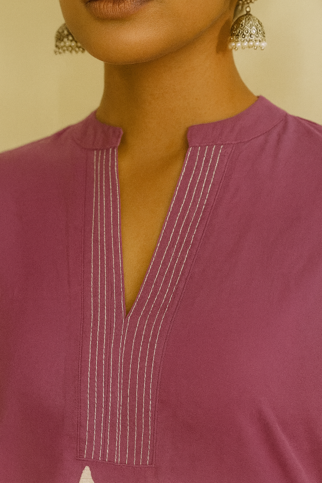 Close-up of a person wearing a purple top with white stitching details.