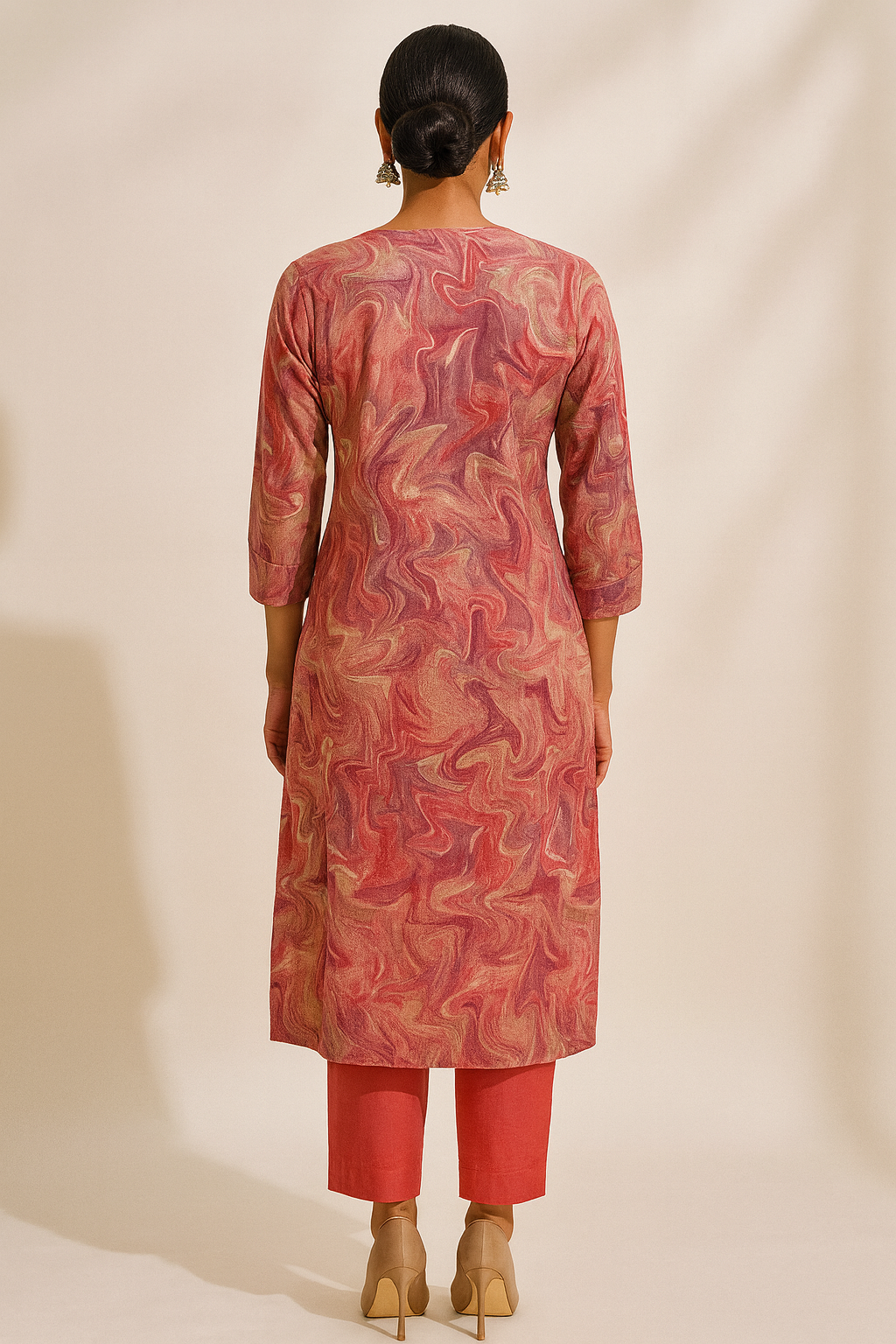 Woman wearing a patterned pink kurta with matching pants on a beige background