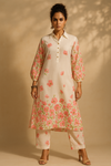 Woman wearing a floral kurta with pants against a beige background